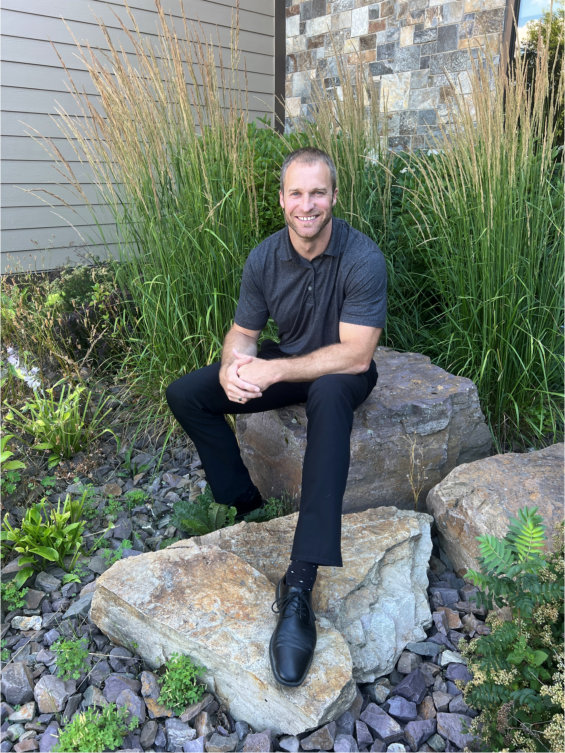 George Mercer, sitting outside of the Hospital on a rock, smiling.